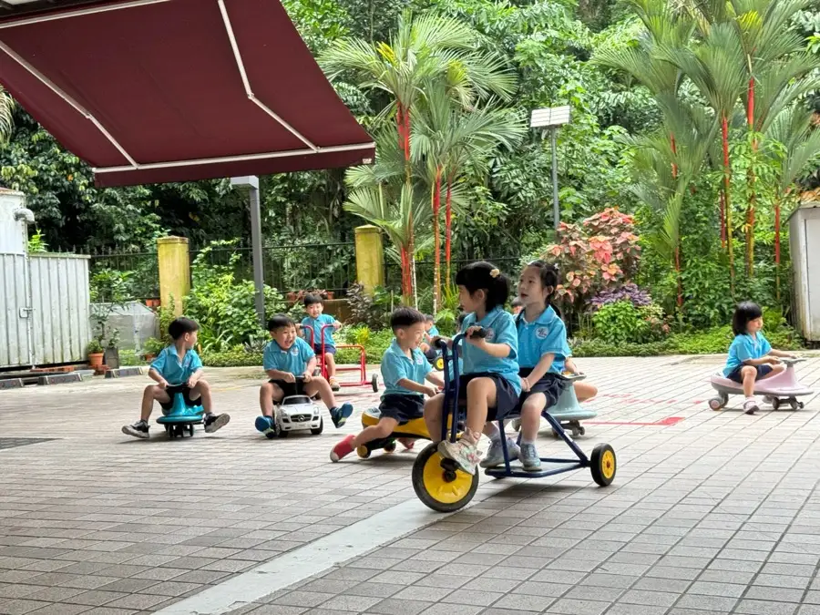 Arise Preschool children riding trikes in the outdoor courtyard